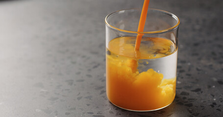 sea buckthorn juice pour into beaker glass with water on concrete surface