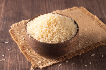 Uncooked white rice in a wooden bowl. Healthy cereal concept