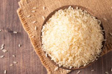 Uncooked white rice in a wooden bowl. Healthy cereal concept