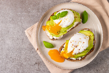 Toast with avocado, soft cream cheese, rye bread and poached Egg. Wholemeal open sandwich for...