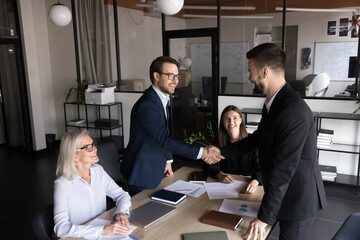 Group of shareholders greeting each other before negotiation in modern conference room, shaking...