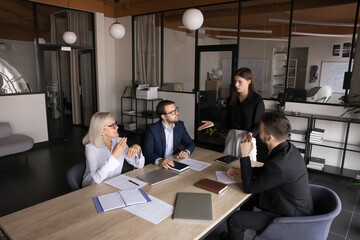 Business partners engaged in negotiations in meeting room led by young female company boss....