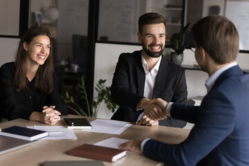 Fototapeta premium Two businessmen shaking hands across table, gesture of trust, agreement, closing of deal. Business parts gather in conference room, start or finalize negotiation feel satisfied, express mutual respect