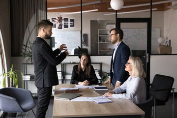 Confident businessman talking to colleague on brainstorming session meeting in modern conference room, offering ideas for joint project, discussing business strategy, disputing. Management, teamwork
