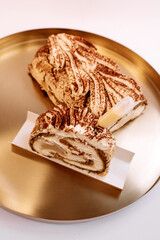 meringue roll sprinkled with chocolate on a golden tray cut in half 