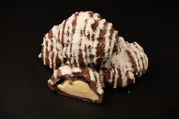 Profiteroles with coconut cream on a black background.