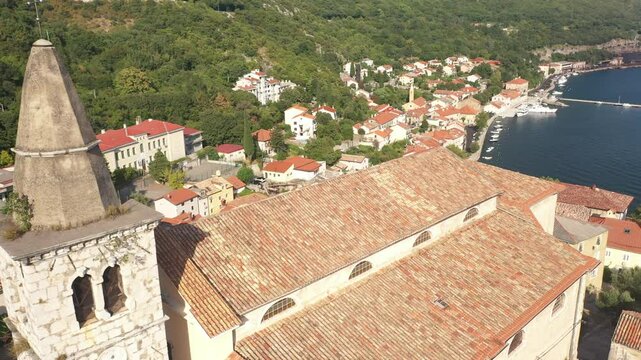This video captures the aerial view of Zupna Crkva Sv. Andrije Apostola in Bakar, Croatia, as it overlooks the Adriatic Sea. The stunning footage showcases the church's proximity to the water, offerin