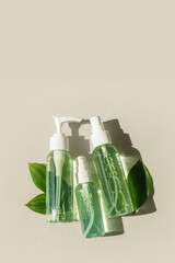 Transparent Cosmetic bottles with green leaf for skin care. Beauty products mockup face lotion, facial cleanser, toner, natural organic cosmetics, minimal top view, summer sunlight, shine shadow