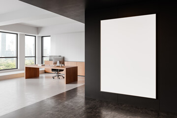 Modern office interior with large, blank framed poster on black wall near wooden desk with office chair and windows overlooking city view. 3D Rendering