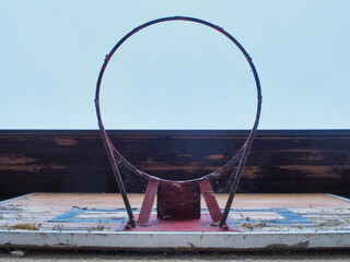 Old Outdoor Basketball Hoop with Rust and Cobwebs Against Blue Sky