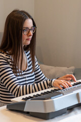 Fototapeta premium Pretty woman playing music on synthesizer keyboard in room