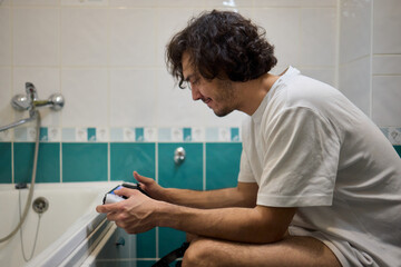 A Man Engaged in a Leisurely Activity While Relaxing in a Comfortable Bathroom Setting