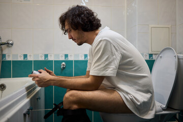 A Man Engaged in a Leisurely Activity While Relaxing in a Comfortable Bathroom Setting