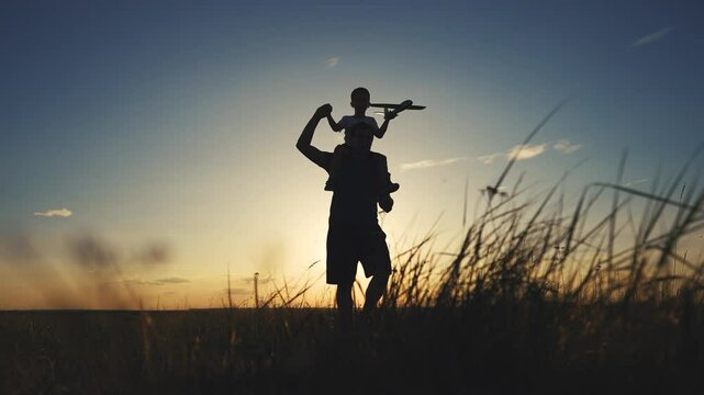 Silhouette of father and son bending his neck. Daughter parent beach concept. A father walks his child around his lifestyle neck. Silhouette of a father and son walking around the neck of a child.