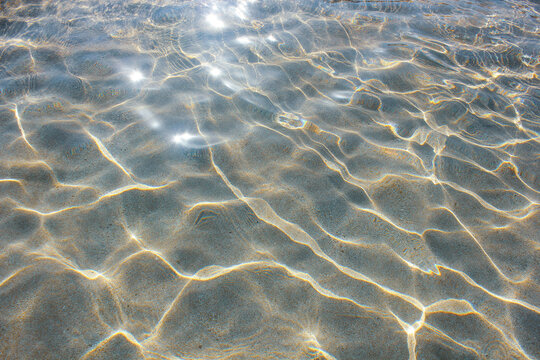 Beautiful shiny sea water surface with sunlight reflections and shadow on bottom.
