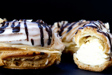 Close-up of a ring-shaped eclair cut in half on a black background.