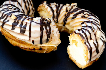 Close-up of a ring-shaped eclair cut in half on a black background.