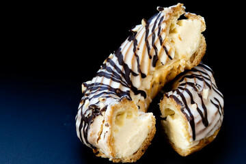 Close-up of a ring-shaped eclair cut in half on a black background.