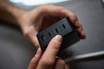 Detailed closeup image of a hand firmly holding a USB hub that features multiple ports