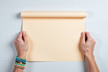 Obraz premium Hands hold beige paper on light gray wooden surface with bracelets