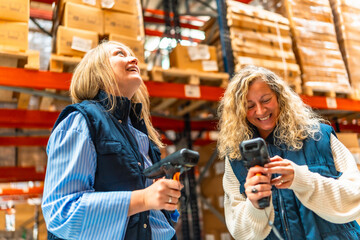 Happy female workers scanning boxes in a warehouse