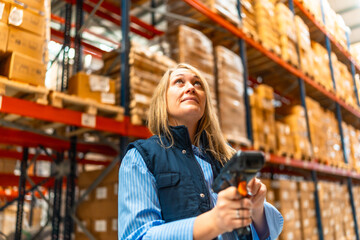 Woman worker scanning package with bar code reader at warehouse