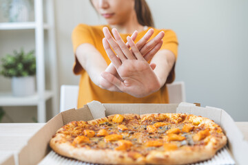 Diet concept, unhappy asian young woman, girl refusing to eat Pizza in box at home, hand pushing...