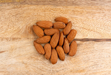Almonds pile, nut group, whole almond seeds, brown scattered fruit kernels, dry raw nuts on wood