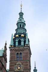 Obraz premium Tower is rectangular with a clock, observation decks and a spire with a flagpole. Freberiksborg Castle