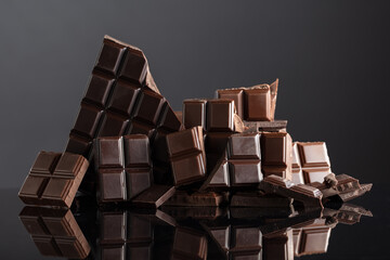 Broken bitter and milk chocolate bars on a black background.
