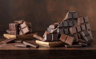 Broken bitter and milk chocolate bars on a brown background.
