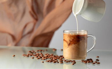 Pouring milk in black coffee.