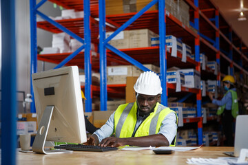 african american warehouse worker using computer checking storage inventory in storehouse . checklist for inventory in warehouse