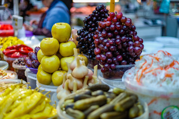 Pickles fruits and vegetables. Pickled apples, hot jalapeno pepper, and grapes are piled high on the market. Organic food