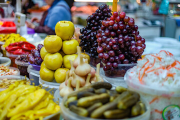 Pickles fruits and vegetables. Pickled apples, hot jalapeno pepper, and grapes are piled high on the market. Organic food