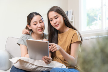 Fototapeta premium two happy women lesbian couple watching series on internet via touchpad relax together.