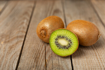 Kiwi on wooden background. Whole fruit and slices pieces of green kiwi on table. fresh ripe juicy kiwi. Tropical fruit. Organic fruit. Healthy eating. Space for text. Copy space.
