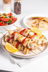 Delicious grilled chicken skewers with capsicum, lemon, salad and ketchup on a plate over the table. Chicken kebab. Healthy food concept.