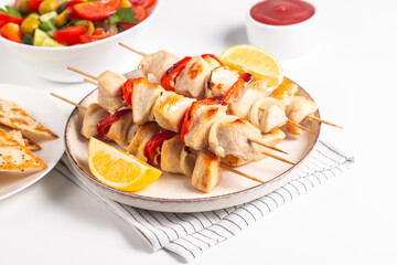 Delicious grilled chicken skewers with capsicum, lemon, salad and ketchup on a plate over the table. Chicken kebab. Healthy food concept.