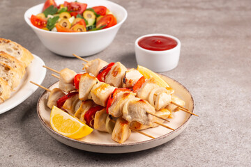 Delicious grilled chicken skewers with capsicum, lemon, salad and ketchup on a plate over the table. Chicken kebab. Healthy food concept.