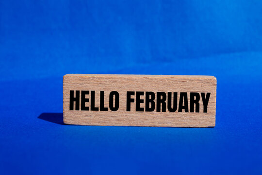 Hello february message written on wooden block with blue background. Conceptual hello february symbol. Copy space.
