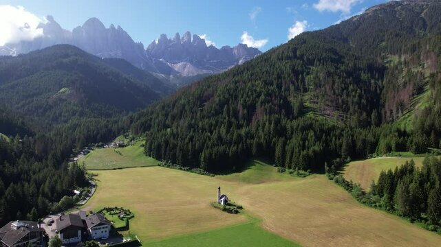 DRONE AERIAL FOOTAGE - The Odle  Group mountain peaks and the Church of St. John in the Valley of Funes, South Tyrol in northern Italy. The small church of Ranui, is a symbol of South Tyrol's beauty.