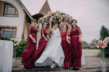 A bride and her bridesmaids are posing for a picture in front of a building. The bride is wearing a...