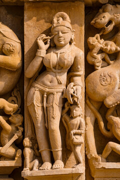 India. Madhya Pradesh state. The Khajuraho Group of Monuments are a group of Hindu and Jain temples. Parshvanatha Jain Temple. Bas relief of a woman putting kohl on her eyes