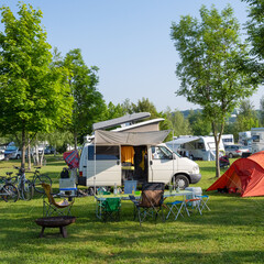Quadratisches Bild eines Campingplatzes mit Wohnmobil, Zelt und Fahrrädern – ideal für...