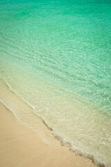 Small Waves incoming at a perfect Tropical Beach with white Sand and crystal-clear turquoise Sea Water with Ripples; Close-up; Copy Space