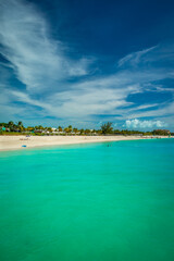 Perfect Caribbean Beach with white Sand, Palm Trees and turquoise Sea Water on a perfect Tropical Summer Day with blue Sky and some Clouds; plenty Copy Space