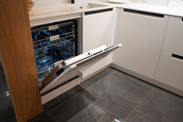 A built-in dishwasher is open, revealing a washer rack in a white kitchen