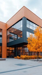 Modern Architecture with Glass Facade, Autumn Tree, and Vibrant Orange Foliage in Urban Environment Against a Cloudy Sky for Inspirational Purpose