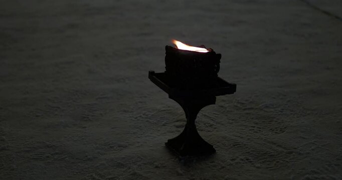 Fire. The flame from a cast iron lamp that stands on the snow sways in the wind and illuminates the space. Hand held.